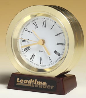 bc917 - solid turned gold aluminum clock on rosewood piano-finished base. black plate, gold color lettering